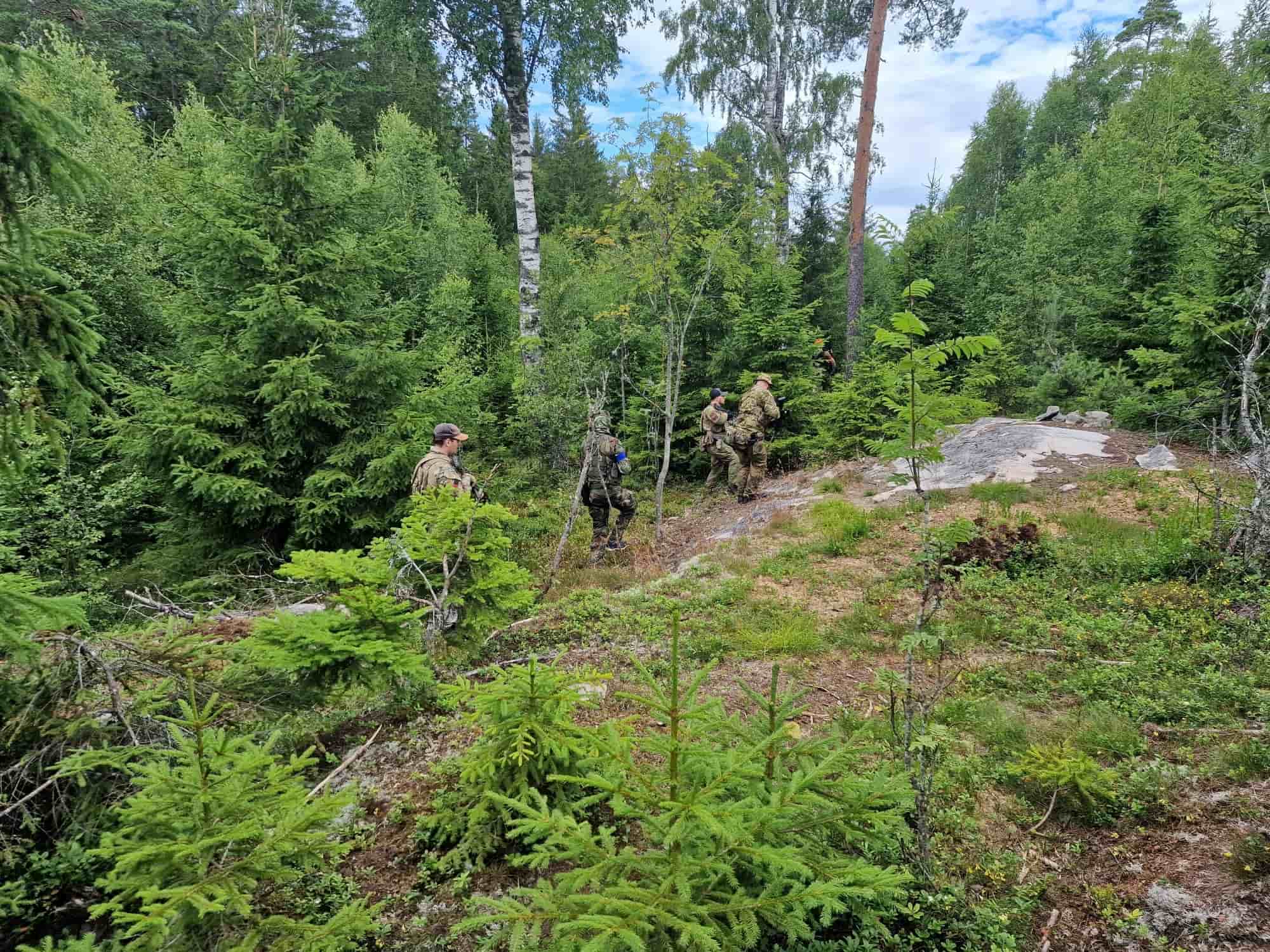 4 guys with fatigues walking through a dense forest.